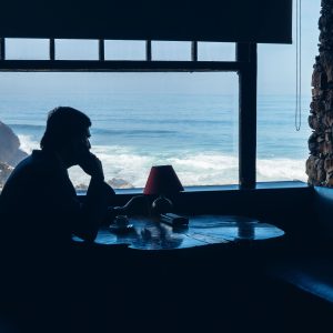 Stillness Satori Insight Timer - When Aloneness Suddenly Feels Like Loneliness. Man sitting at a window looking out to sea.
